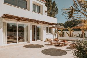 a house with a patio with chairs and umbrellas at Casa Stellar - boutique villa with private pool and sea view - sustainably solar powered in Sant Josep de sa Talaia
