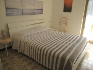a bed in a white room with a striped blanket at Appartamento Island Brioni in Grado-Pineta