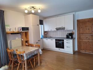 a kitchen with white cabinets and a table and chairs at Medemstern I in Otterndorf +4 photos