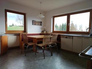 a kitchen with a table and chairs and two windows at greenlodge pornplatthof in Auna di Sopra