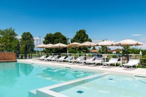 a swimming pool with chairs and umbrellas at BORGO STALIS RESORT in Sesto al Reghena