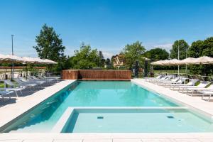 a swimming pool with chairs and umbrellas at BORGO STALIS RESORT in Sesto al Reghena