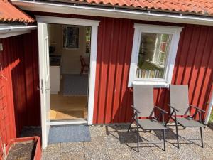 two chairs sitting outside of a red house at Gäststuga på Tjörn in Rösselvik