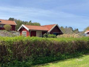 a red house with a red roof in a field at Gäststuga på Tjörn in Rösselvik