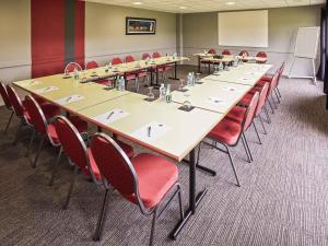 a large conference room with a long table and red chairs at Ibis Auray in Auray