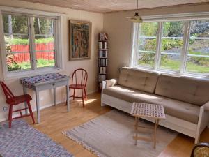 a living room with a couch and a table and windows at Gäststuga på Tjörn in Rösselvik +1 photo