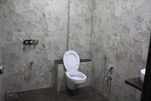 a bathroom with a toilet and a shower at Royal Palace Hotel Surat Velanja in Sāyan