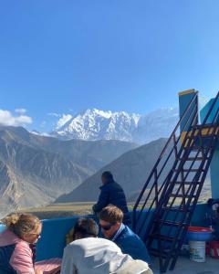 a group of people sitting next to a ladder at Hotel Tara in Kāgbeni