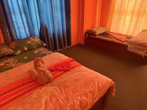 a room with a bed with a stuffed animal on it at Hotel Tara in Kāgbeni