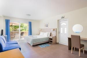 a bedroom with a bed and a desk and a window at Hotel Estia in Finikounta