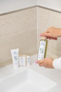 a person holding a bottle of lotion in a bathroom at Country Hotel Residence Da Pilade in Capoliveri