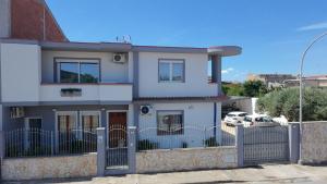 a white house with a fence in front of it at Corona Guest House in Sestu