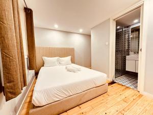 a bedroom with a white bed and a bathroom at Torrinha's Backyard in Porto