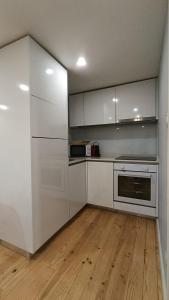 a kitchen with white cabinets and a wooden floor at Torrinha's Backyard in Porto +35 photos
