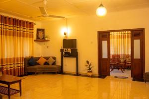 a living room with a couch and a television at Villa Serene Herbs Dickwella in Dickwella