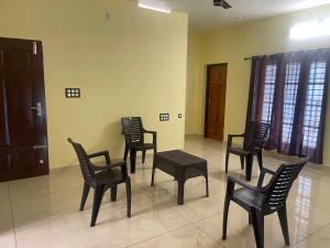 a group of chairs and a table in a room at Cozi Rooms in Varkala