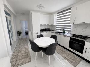 a white kitchen with a white table and chairs at Apartament Bucovina Bellevue in Gura Humorului