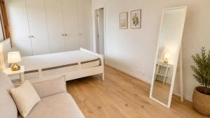 a white bedroom with a bed and a mirror at La maison IDEL in Yvonand +3 photos