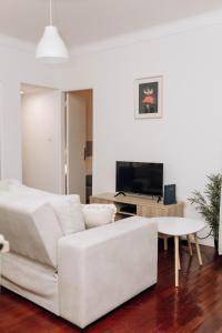 a white living room with a white couch and a tv at Encanto do Lima Guest House By Lethes Legacy in Ponte de Lima