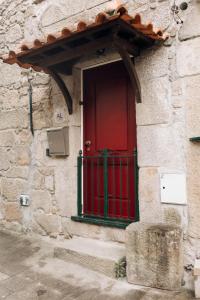 a red door on the side of a stone building at Encanto do Lima Guest House By Lethes Legacy in Ponte de Lima