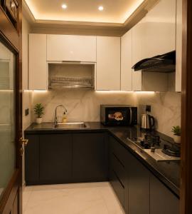 a kitchen with black and white cabinets and a sink at Emerald Villa Islamabad in Islamabad