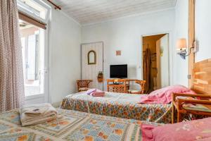 a bedroom with two beds and a television in it at Côté Jardin in Bédoin