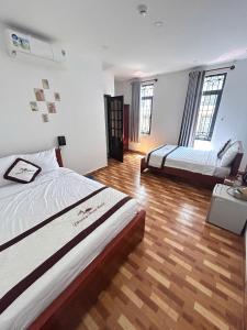 two beds in a room with wooden floors and windows at Khách sạn Phương Danh in Phú Tài (1) +14 photos