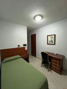 a hotel room with a bed and a desk and a desk at Hostal Blumen in Algeciras