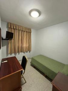 a room with a bed and a desk and a window at Hostal Blumen in Algeciras