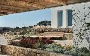 a wooden bench sitting next to a stone wall at Koufonisi Villa Kallisti in Koufonisia