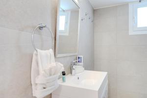 a white bathroom with a sink and a mirror at Salt & Sun Retreat in Perivolia +46 photos