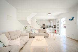 a white living room with two couches and a table at Salt & Sun Retreat in Perivolia