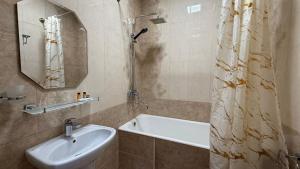 a bathroom with a sink and a tub and a shower at Giza Grand Hotel in Tashkent