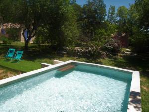 a swimming pool in a yard with two blue chairs at Gîte au calme l'eclaircie in Régusse