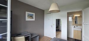 a living room with a white wall and a kitchen at Logis Auberges des Aulnettes in Houlgate