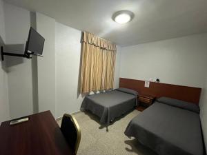 a room with two beds and a desk and a table at Hostal Blumen in Algeciras