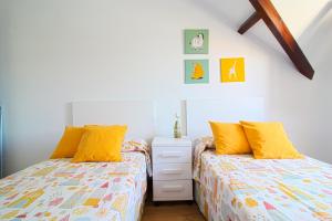 two beds with yellow pillows in a bedroom at Apartamento Arena Dorada in Somo