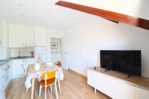 a kitchen with a dining room table and a flat screen tv at Apartamento Arena Dorada in Somo +9 photos