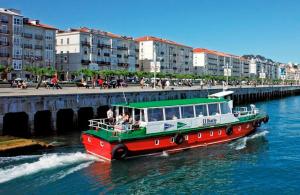 a red and green boat in the water near a bridge at Apartamento Arena Dorada in Somo