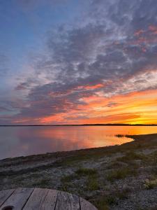 a sunset over a body of water with a wooden pier at Merevaatega Glämping Sarvel in Kukka