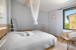 a white bedroom with a bed and a window at Le Logis des Abeilles in Lapenne