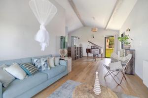 a living room with a blue couch and a piano at Le Logis des Abeilles in Lapenne
