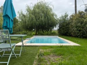 a pool with a table and a chair and an umbrella at Chez Annie et William in Montpouillan