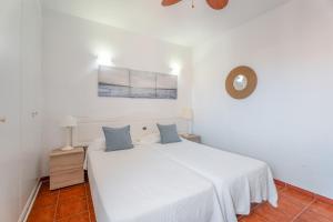 a white bedroom with a white bed with blue pillows at Casa Perla in Playa de Santiago +15 photos