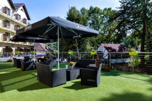 a group of chairs under an umbrella on the grass at Krasicki Hotel Resort & Spa in Świeradów-Zdrój