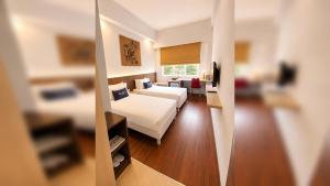 a hotel room with a bed and a mirror at Kyriad Arra Hotel Cepu in Cepu