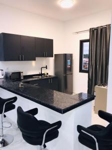 a kitchen with a black counter top and black chairs at THE TIMES HOUSE, Toit panoramique vue mer & groupe électrogène in Libreville