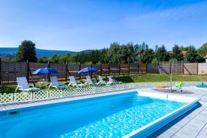 a swimming pool with chairs and umbrellas in a yard at Krasicki Hotel Resort & Spa in Świeradów-Zdrój