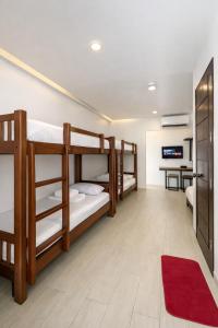 a room with three bunk beds and a red rug at Mayumi Lodge in Puerto Princesa City +23 photos