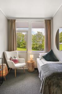 a bedroom with a bed and a chair and a window at A11 Apartments in Ålesund